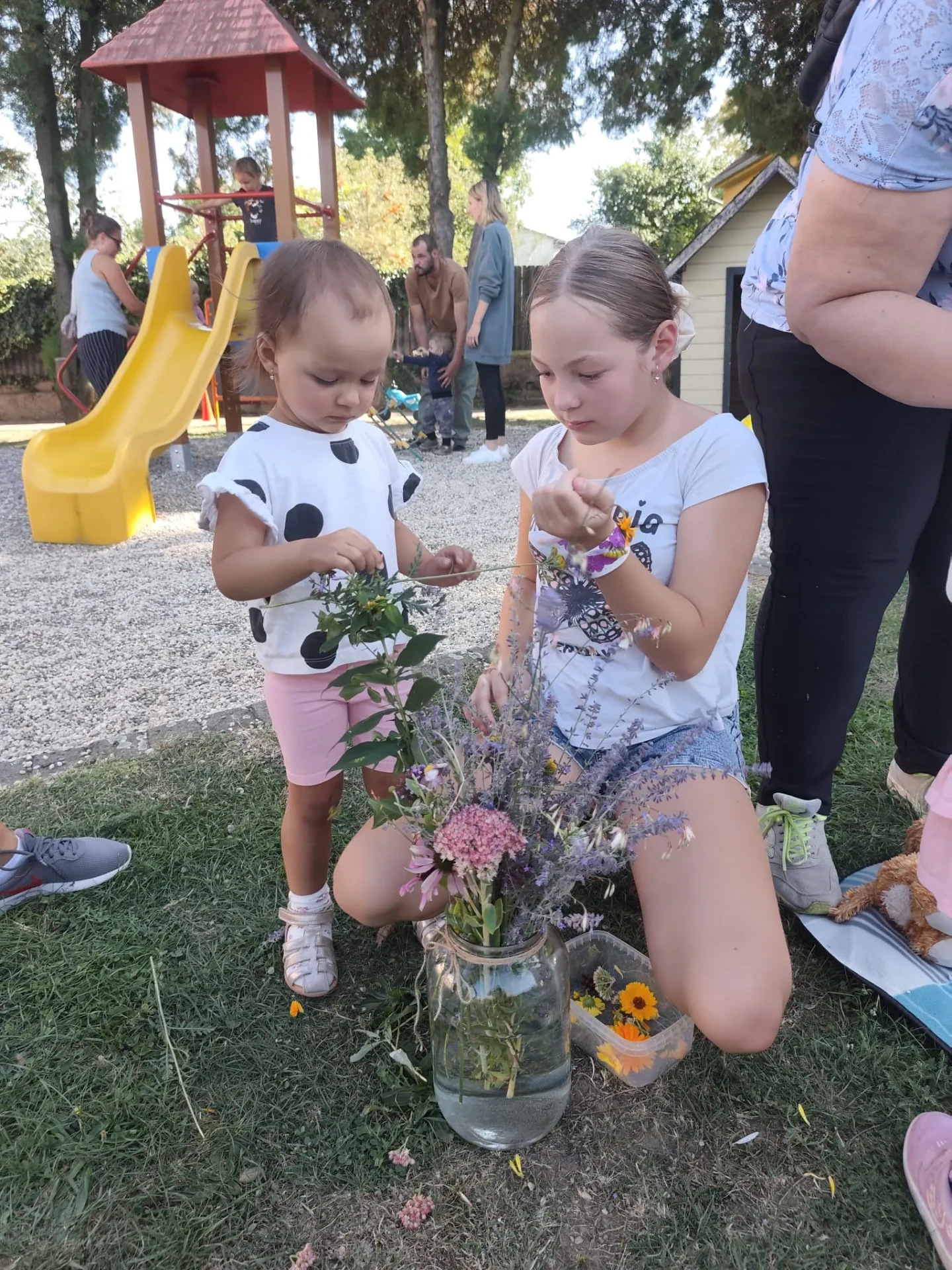 Děti vázají kytičky z bylinek a květin na školní akci