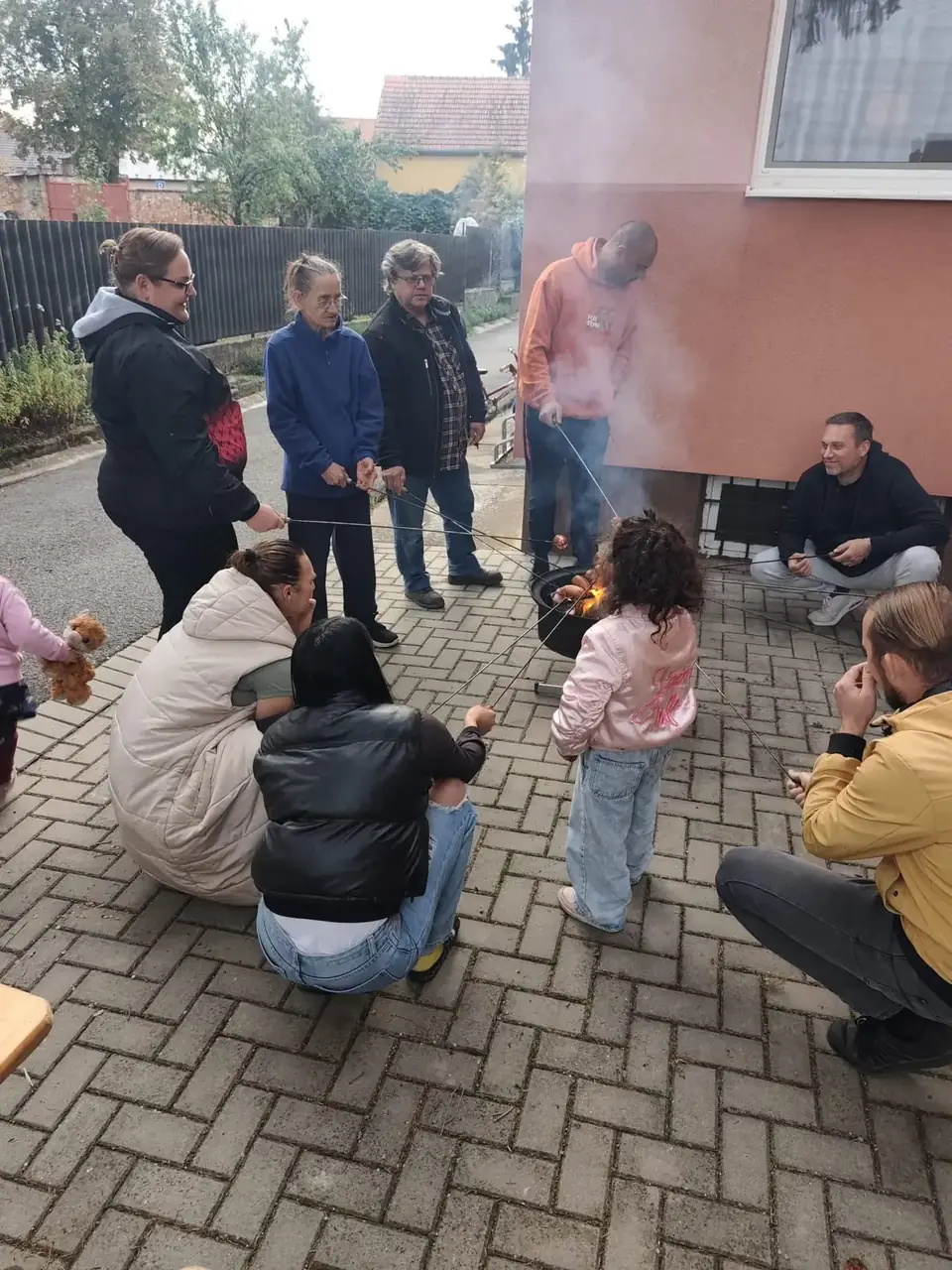 Rodiče a děti opékají špekáčky u ohniště venku