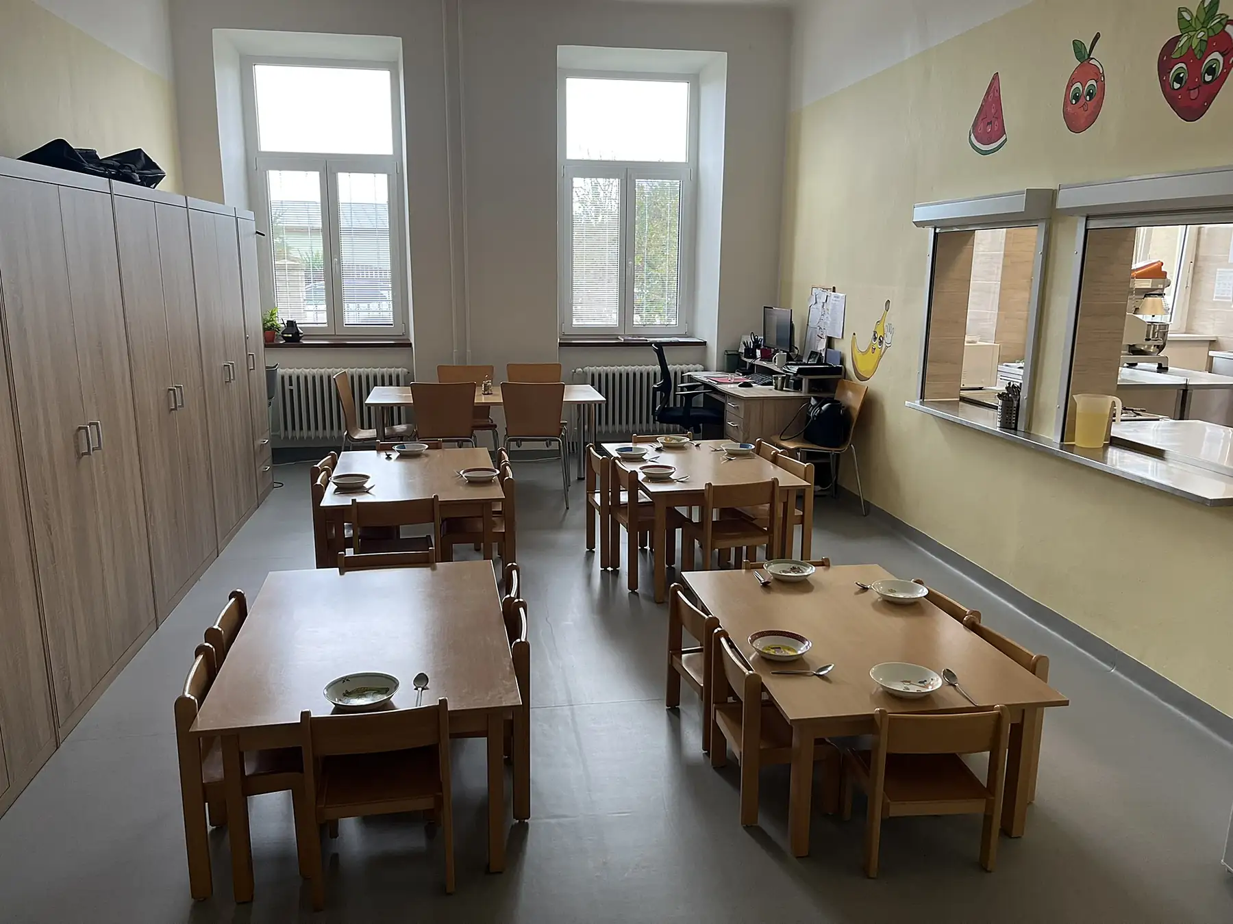 Jídelna s dřevěnými dětskými stoly a židlemi