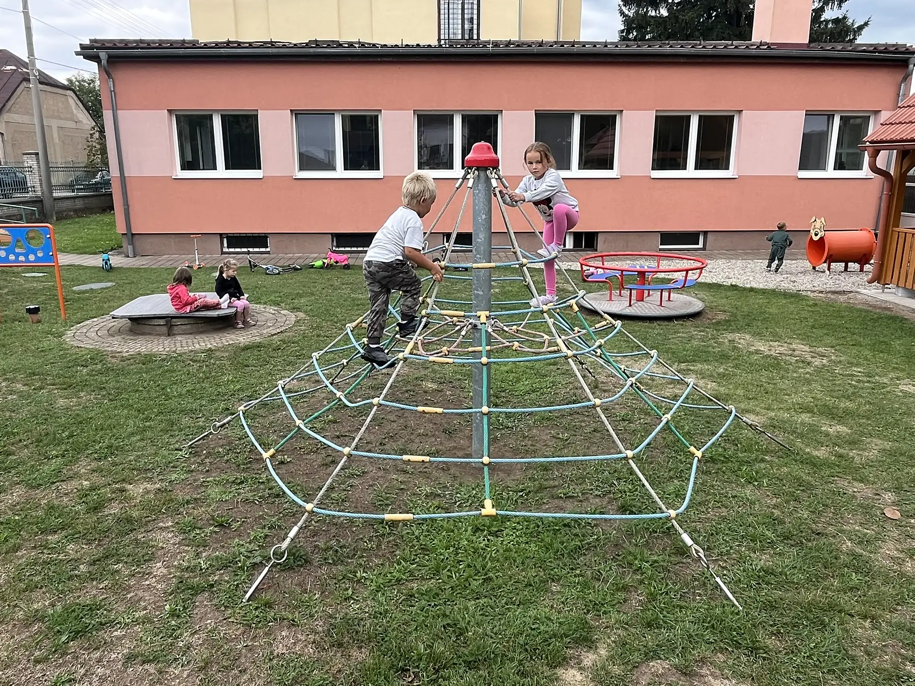 Děti na lanové lezecké síti na zahradě školky